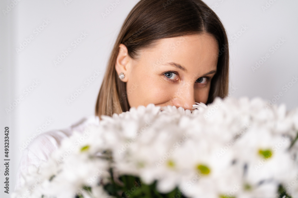 Good looking Caucasian woman smells flowers, she is happy for get a fresh bouquet of white chrysanthemum