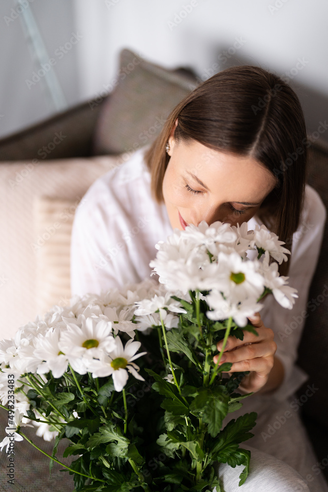 Good looking Caucasian woman smells flowers, she is happy for get a fresh bouquet of white chrysanthemum Good looking Caucasian woman smells flowers, she is happy for get a fresh bouquet of white chrysanthemum
