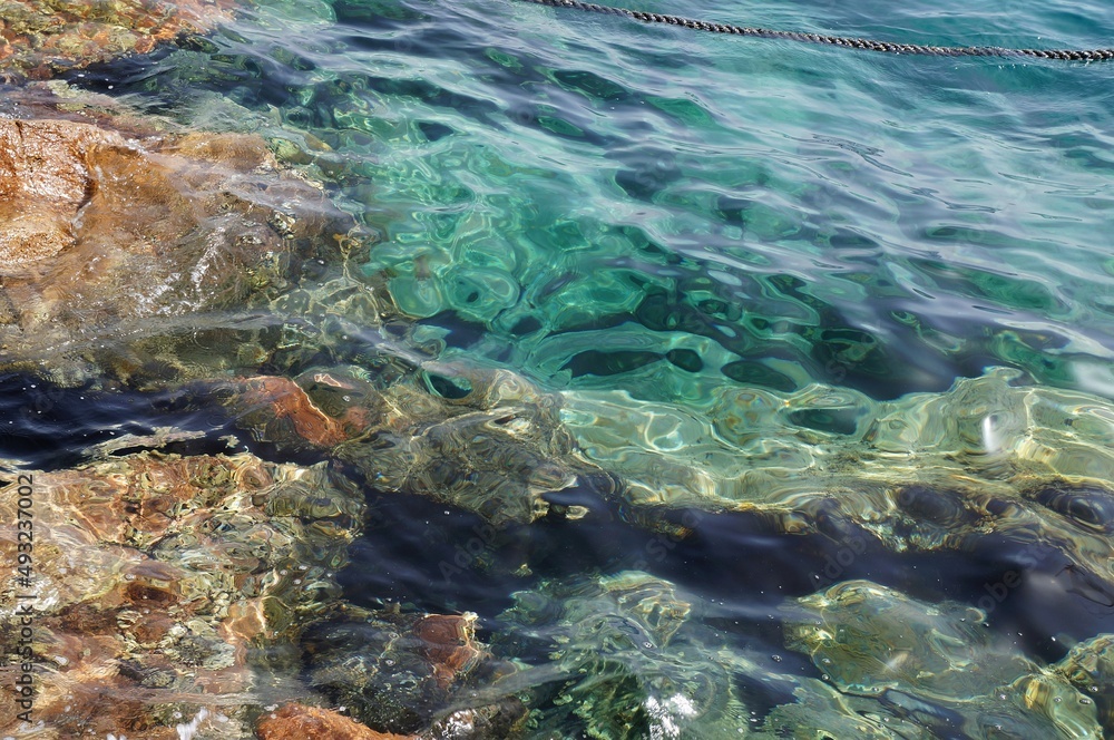 Clear sea water surface, stones and glare Clear sea water surface, stones and glare