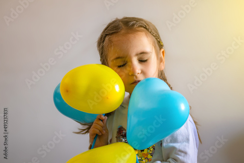 A sad child holds balloons, in the yellow-blue colors of Ukraine © Irina Flamingo