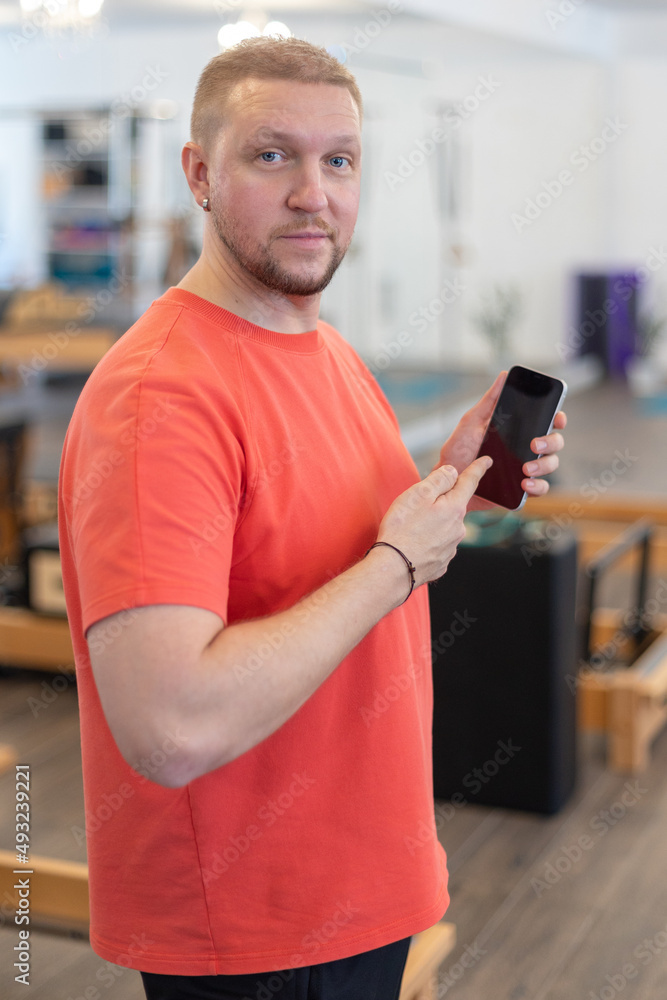 Portrait of confident man in red showing smartphone screen, smiling to camera. High quality photo Portrait of confident man in red showing smartphone screen, smiling to camera. High quality photo