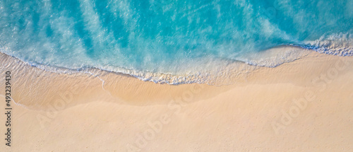 Summer seascape beautiful waves, blue sea water in sunny day. Top view from drone. Sea aerial view, amazing tropical nature background. Beautiful bright sea with waves splashing and beach sand concept © icemanphotos