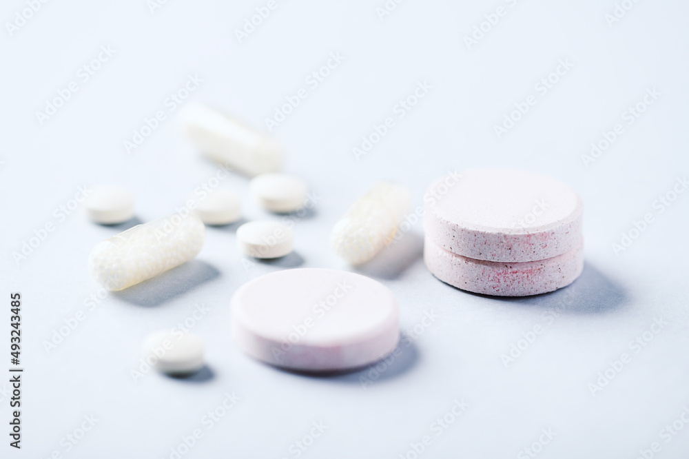 Collagen effervescent Tablets and Vitamin C tablets and capsules. Supplements to support collagen production. Bright paper background. Soft focus. Close up. Collagen effervescent Tablets and Vitamin C tablets and capsules. Supplements to support collagen production. Bright paper background. Soft focus. Close up.