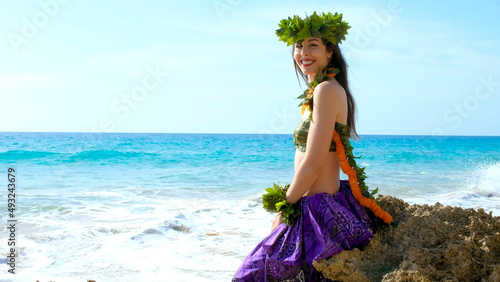 Hawaiian woman enjoys hula dancing on the beach barefoot wearing traditional costume