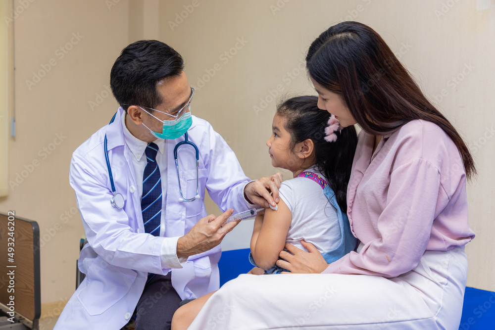 Young woman pediatrician performs a vaccination of a little girl. Looks at the doctor. Young woman pediatrician performs a vaccination of a little girl. Looks at the doctor.
