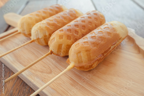 Homemade Waffle sausage sticks on wooden dish ready to serve and wooden table background . Trendy bakery street food.
