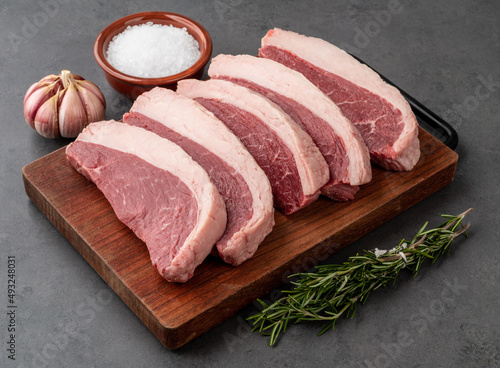 Sliced raw picanha or rump meat over wooden board with seasonings