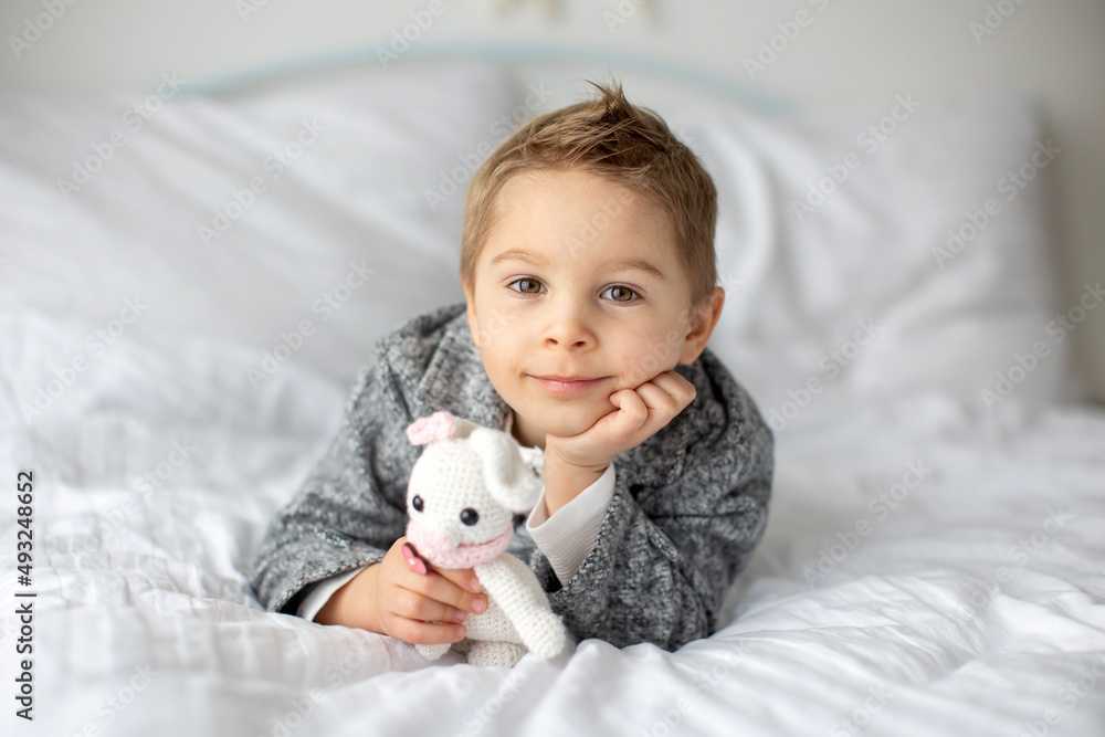 Cute stylish toddler child, boy with white shirt, playing with eggs and chocolate bunny on Easter decoration Cute stylish toddler child, boy with white shirt, playing with eggs and chocolate bunny on Easter decoration