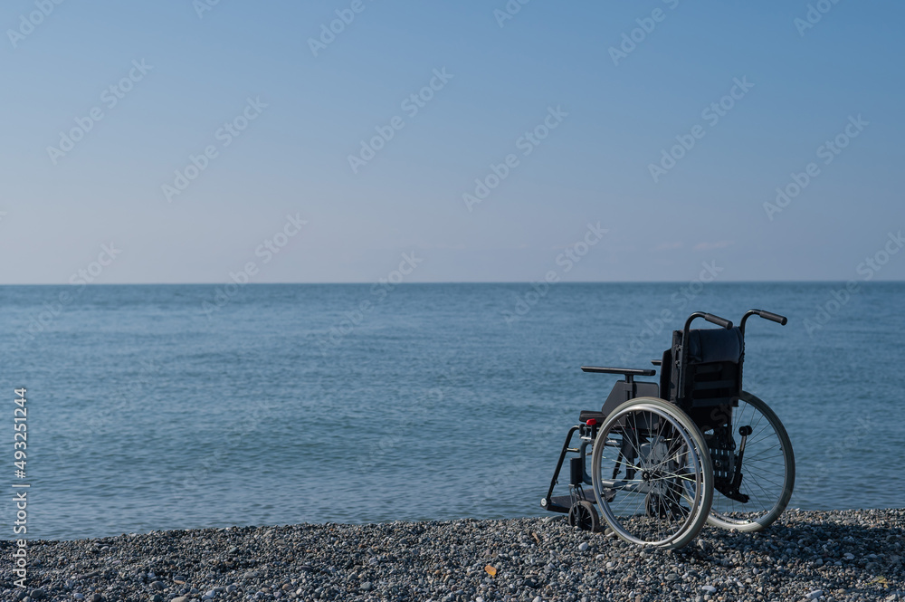 Fototapeta premium An empty wheelchair on a rocky seashore.