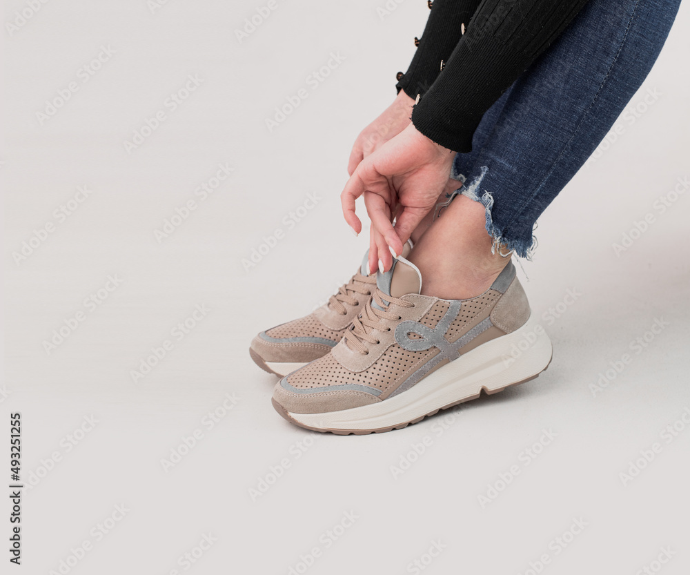 Women's legs in stylish sports shoes on a white background Women's legs in stylish sports shoes on a white background