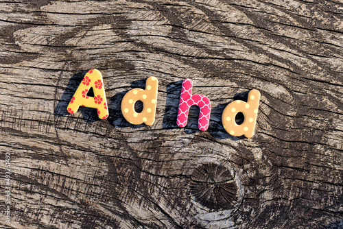 Letters ADHD written on colorful toy text on wooden surface. Attention deficit hyperactivity disorder concept. photo