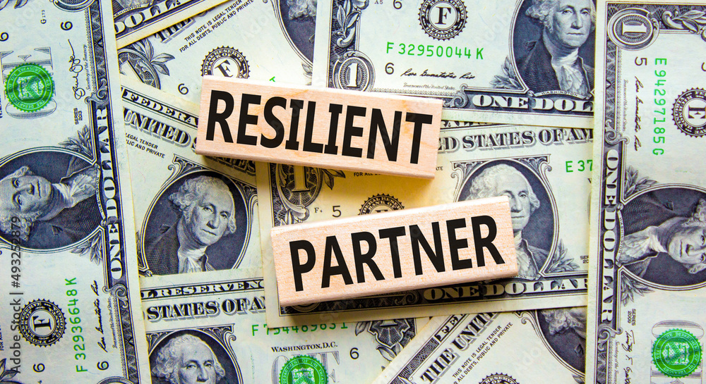 Resilient partner symbol. Concept words Resilient partner on wooden blocks on a beautiful background from dollar bills. Business resilience and resilient partner concept, copy space.
