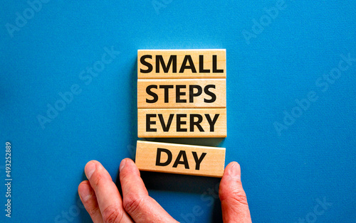 Small steps every day symbol. Concept words Small steps every day on wooden blocks. Businessman hand. Beautiful blue table blue background. Small steps every day business concept. Copy space. photo