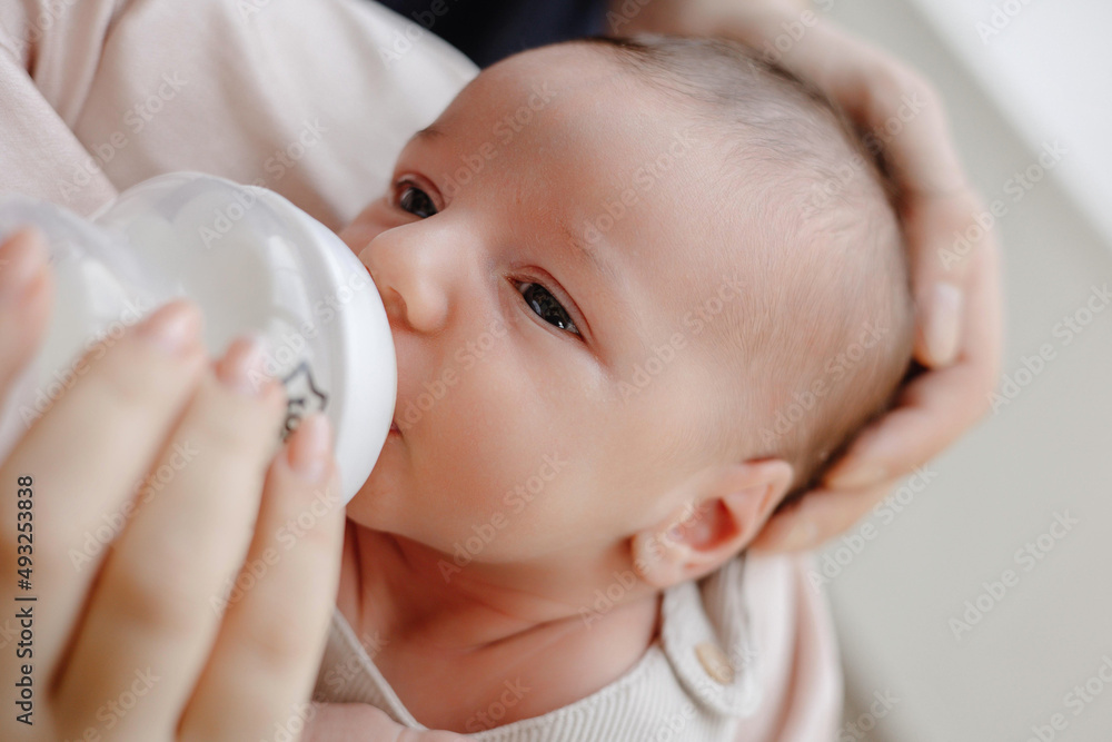 Beautiful baby drinking milk, close up baby drinking milk from baby bottle with mother Beautiful baby drinking milk, close up baby drinking milk from baby bottle with mother