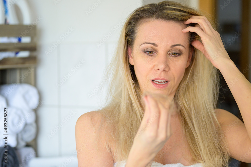 Forty year old woman looking at a tuft of her hair