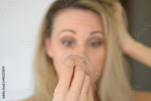 Woman looking at a loose tuft of hair in consternation