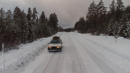 Old car in the swedish snowy roads between the forests. Car driv