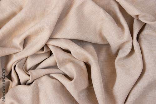 Texture of beige fabric. Background with folds. Close-up.
