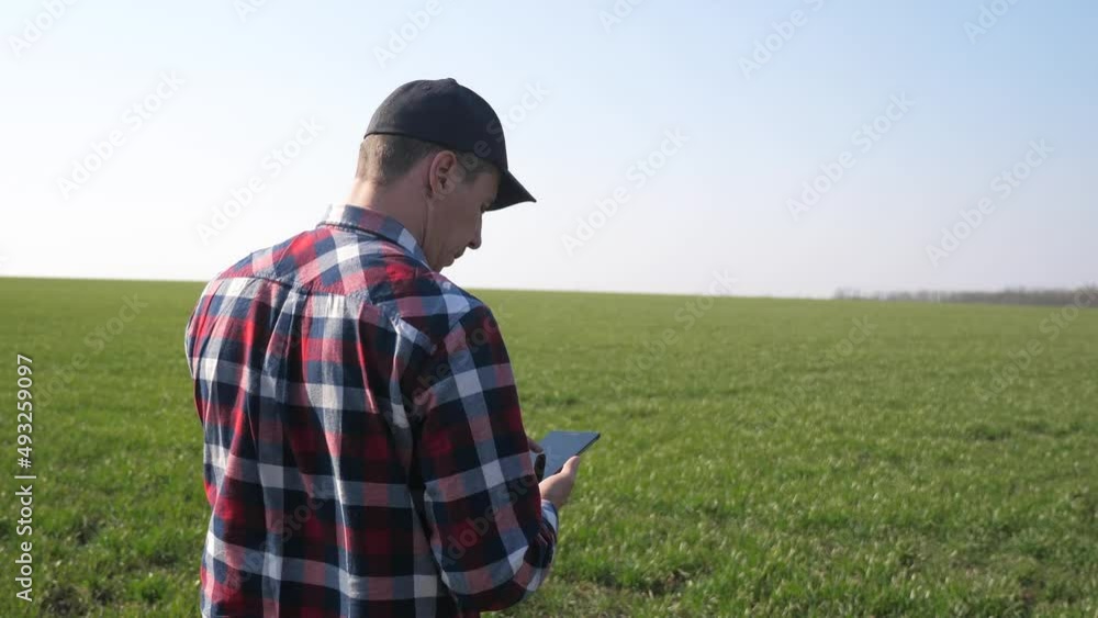 man farmer red neck with a digital tablet walking on land for sowing on a green field. eco farming agriculture concept lifestyle . male worker studies winter green wheat crops works in field man farmer red neck with a digital tablet walking on land for sowing on a green field. eco farming agriculture concept lifestyle . male worker studies winter green wheat crops works in field