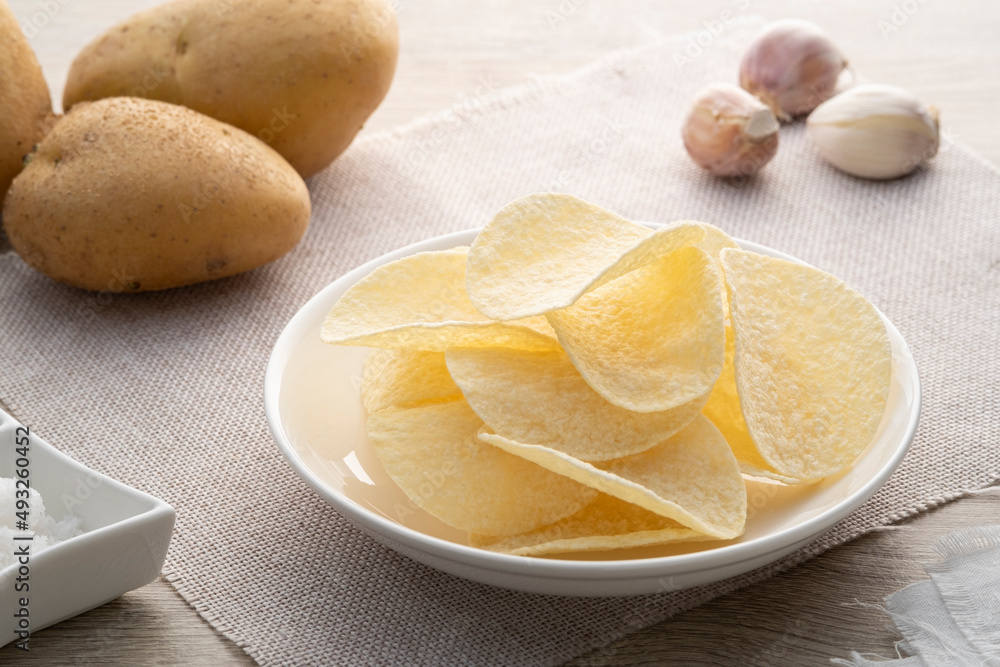 crispy potato chips snack in white plate on wooden table crispy potato chips snack in white plate on wooden table