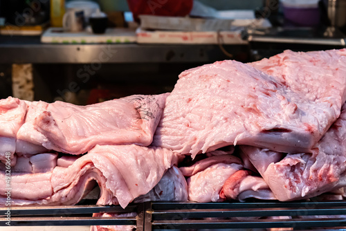 Thick, fat pork and rind cut into pieces in a market stall. Food material full of collagen and axunge. photo