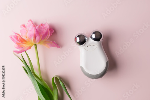 Fotografie microcurrent toning device for facial massage on color background with tulip flower