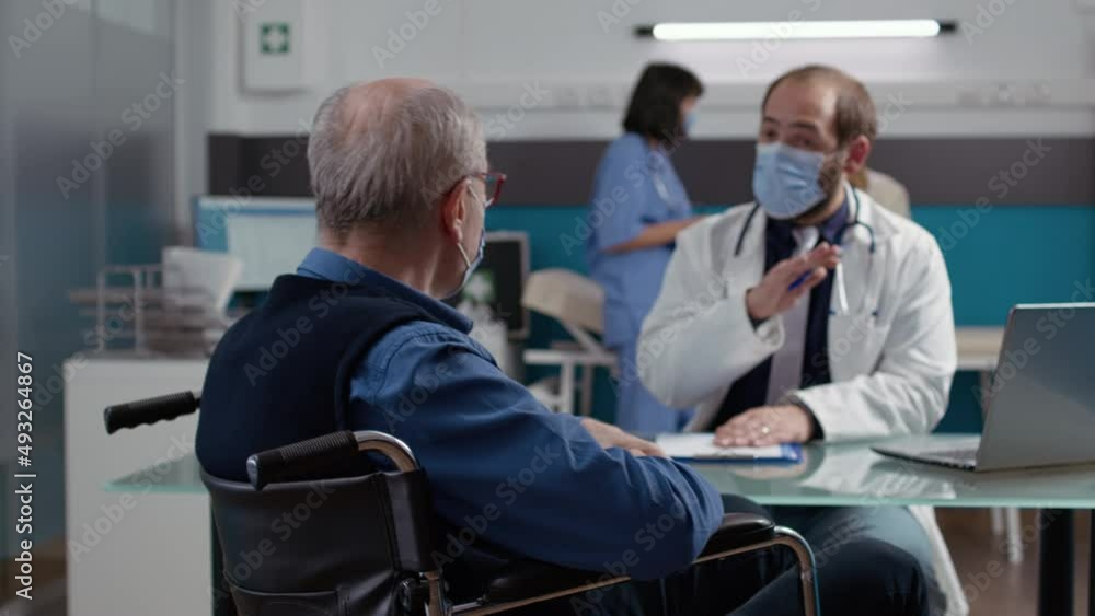 Male patient in wheelchair doing consultation with medic at checkup