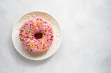 Pink donut with sprinkles on bright background, sweet food