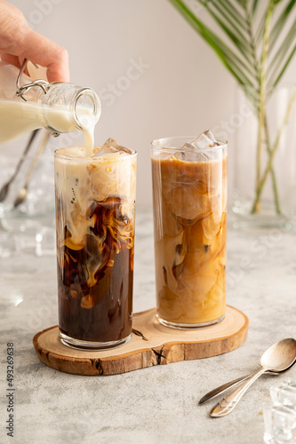 Iced coffee in glass. Pouring milk in glass with coffee. Summer drink. photo