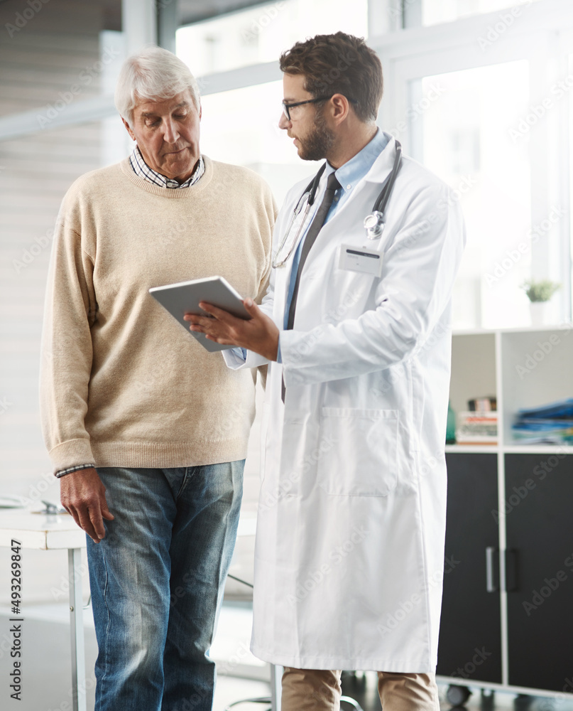 So this link will bring up all your medical history. Cropped shot of a young male doctor showing his senior male patient something on a digital tablet. - obrazy, fototapety, plakaty 