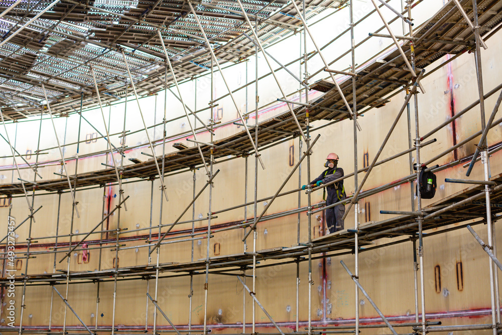 Worker male assembly in progress storage tank oil inspection scaffolding work at high