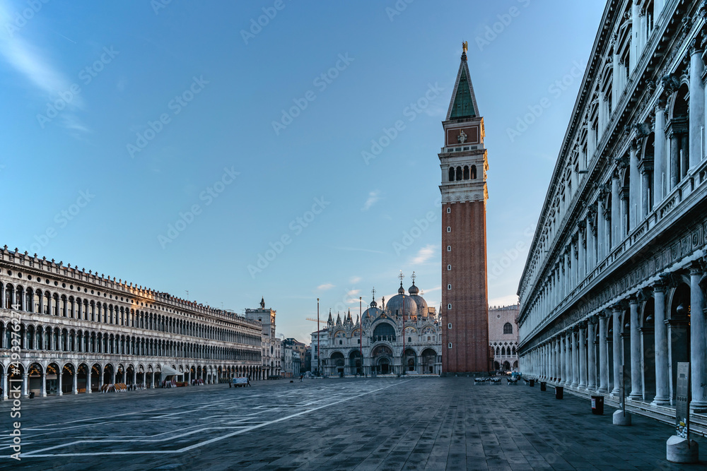 Famous empty San Marco square with Basilica of Saint Mark and Bell Tower at sunrise,Venice,Italy.Early morning at popular tourist destination.World famous Venice landmarks.Postcard view,travel scenery