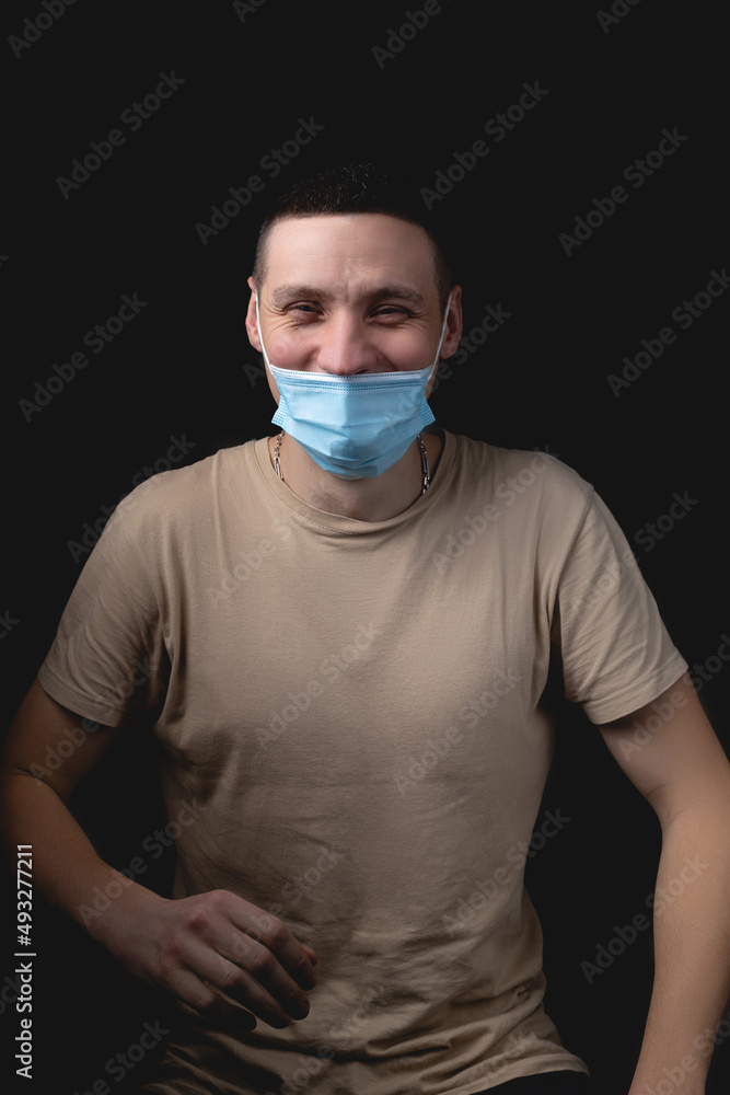 Handsome young man and a medical mask on a black background. Handsome young man and a medical mask on a black background.