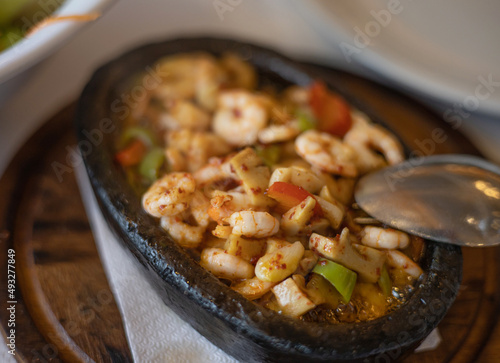 Fried shrimps with vegetables in cast iron frying pan. Menu in a restaurant. Close up