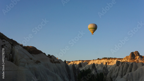 Hot air balloon over the ground in the blue sky in sunrise, Cappadocia, Turkey