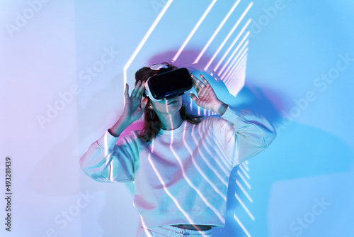 Woman in VR headset near wall with glowing lights photo