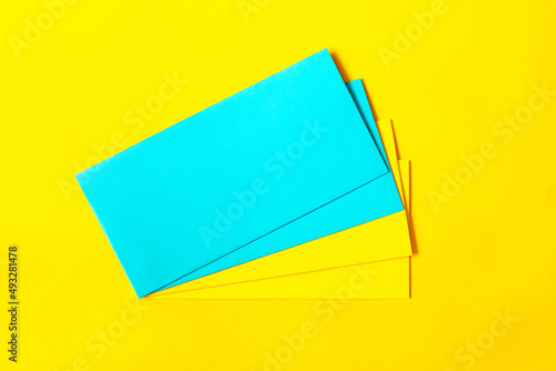 Blue and blue envelopes on a yellow paper background. Copy space, top view