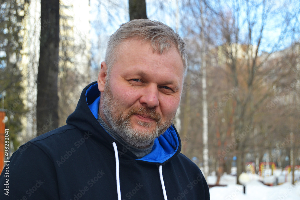A man with a gray beard on the street in winter looks at the camera A man with a gray beard on the street in winter looks at the camera