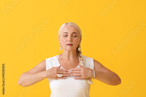 Meditating mature woman on color background photo