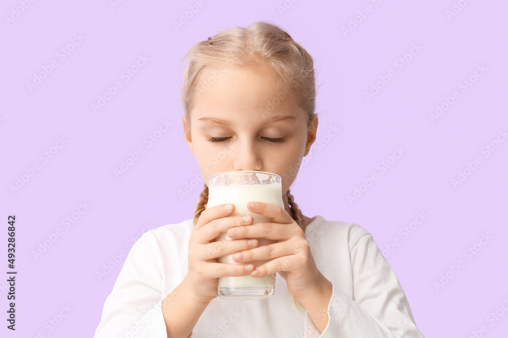 Cute little girl drinking milk on lilac background Cute little girl drinking milk on lilac background