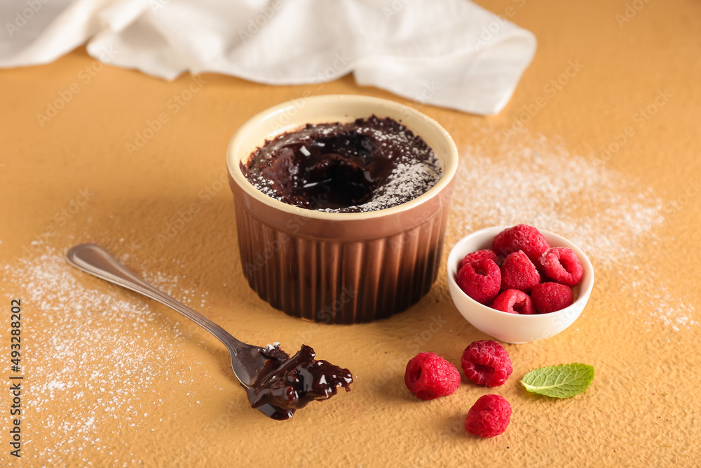 Ramekin with tasty lava cake and raspberries on color background Stock