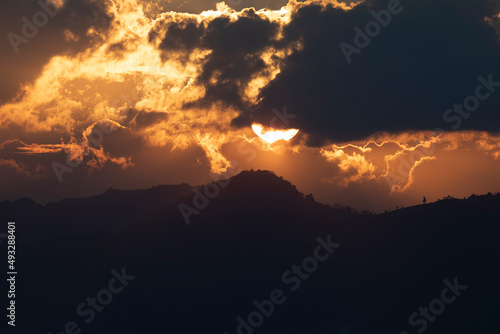 Landscape of mountains, clouds and a huge sunset sun against a tiny temple high above, near Inle Lake, Nyaungshwe, Shan State, Burma, Myanmar,