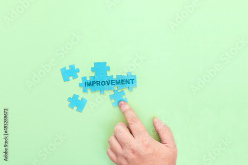 Businessman connecting puzzle pieces with the word Improvement photo