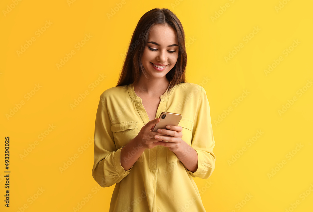 Beautiful young woman with mobile phone on yellow background Beautiful young woman with mobile phone on yellow background