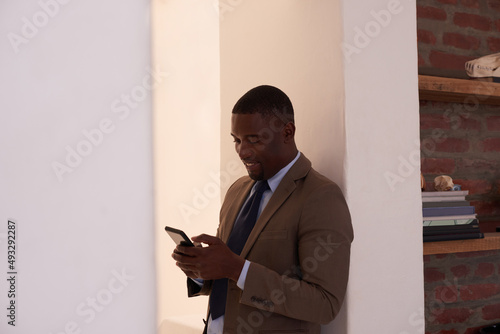 Sending out some texts to new clients. Shot of a young businessman using a cellphone in an office.