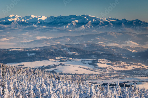 Fototapeta Naklejka Na Ścianę i Meble -  Winter sunset seen from Pilsko in Beskid Żywiecki. Beautiful views of the Tatras and the Mala Fatra massif, bathed in golden light.