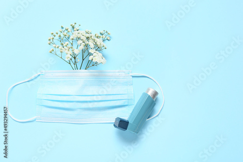 Gypsophila flowers, medical mask and inhaler on color background