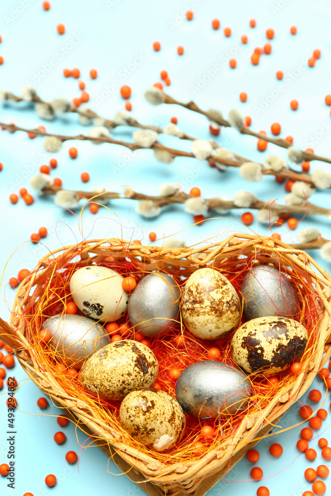 Obraz premium Basket with painted Easter eggs and willow branches on blue background