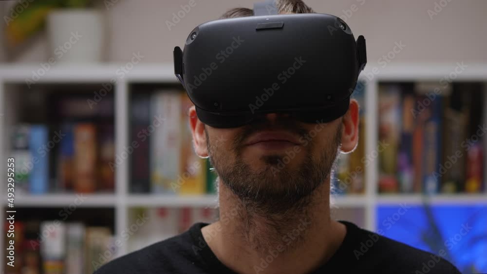 Close-up of a Caucasian man in a black sweatshirt wearing VR glasses on his head and smiling. Home interior. VR helmet for entertainment, education, and gaming Close-up of a Caucasian man in a black sweatshirt wearing VR glasses on his head and smiling. Home interior. VR helmet for entertainment, education, and gaming
