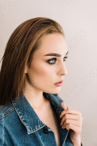Brunette girl wearing denim jacket. Bright evening makeup, smoky eyes, close up portrait